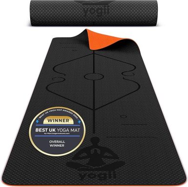 Black yoga mat with orange underside and markings for alignment.