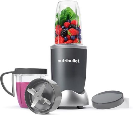 A NutriBullet blender with smoothie cup and lid, filled with green and berry ingredients.